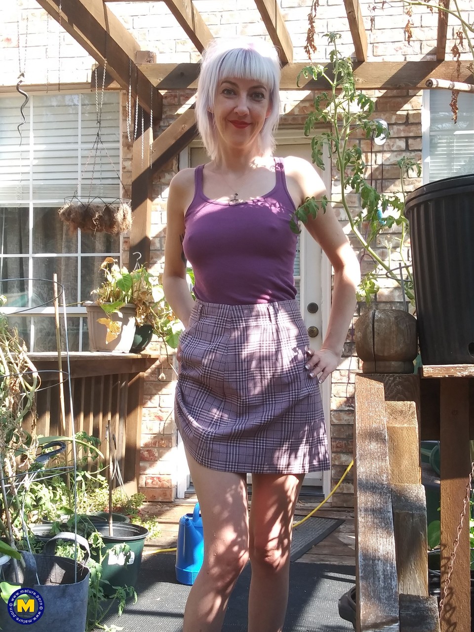 Skinny blonde in a skirt Sylvie J flashing her pussy in an indoor garden