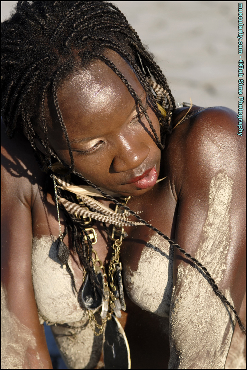 Ebony bodybuilder Camille Elizabeth covers her naked breasts with sand